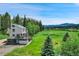 Charming two-story home featuring a spacious deck overlooking a lush green landscape with mountain views at 7614 Malamute Dr, Evergreen, CO 80439