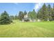 Rear exterior of the mountain home showing deck, shed, landscaping, and mature trees at 7614 Malamute Dr, Evergreen, CO 80439