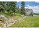 Mountain home featuring a rock water feature, mature trees and three car garage at 7614 Malamute Dr, Evergreen, CO 80439