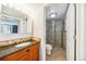 Well-lit bathroom with wood vanity, a dark countertop, and a shower with glass doors in a tiled stall at 1020 15Th St # 13K, Denver, CO 80202