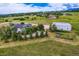 An elevated view shows a modern home, oversized outbuilding, and gardens on large acreage at 16710 Vincent Ave, Monument, CO 80132