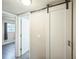 Hallway boasts a barn door feature, neutral colored walls, and an entrance to a bedroom at 6104 Hudson St, Commerce City, CO 80022