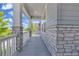 Covered front porch featuring stone columns and a white railing, offering a welcoming outdoor space at 8772 S Sicily Ct, Aurora, CO 80016