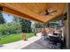 Backyard patio with covered seating area overlooking large lawn with trees and shrubs at 5225 S Everett Ct, Littleton, CO 80123