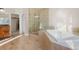 Bathroom with a walk-in shower, tile surround, soaker tub, wood floor and a double sink vanity at 10488 Bluffmont Dr, Lone Tree, CO 80124