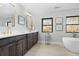 Bathroom featuring double vanity with dark cabinets, framed mirrors, and soaking tub at 3041 S Bellaire S St, Denver, CO 80222