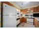 Small kitchen with wood cabinets, white appliances, and floral wallpaper at 3445 S Ammons St # 15-4, Lakewood, CO 80227