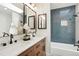 Modern bathroom featuring wood cabinets, double sinks, designer mirrors, and accent wall tile at 202 Hoover Ave, Louisville, CO 80027