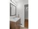 Modern bathroom with a wooden vanity, white countertop, and a well-lit mirror above the sink at 5140 W 9Th Ave, Denver, CO 80204