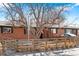 Brick home featuring a well-kept lawn and a sturdy fence, with mature trees providing shade at 5140 W 9Th Ave, Denver, CO 80204