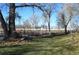 A spacious backyard featuring mature trees, lush grass, and white fencing at 7250 County Road 5, Erie, CO 80516