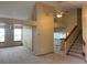 Open-concept living area with neutral carpet, paint and an adjacent staircase with wood railing at 4812 S Bahama Way, Aurora, CO 80015