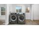 Laundry room showcasing side-by-side washer and dryer with updated tile flooring and natural light at 2601 W Amherst Ave, Denver, CO 80236