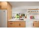 Modern kitchen showcasing countertops, white appliances, and open shelving with a view into a living area at 2445 Vance St, Lakewood, CO 80214