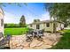 A charming stone patio features a dining table and chairs set against a lush backyard at 2445 Vance St, Lakewood, CO 80214