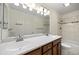 Bathroom with double sinks, wood cabinets, and tiled tub surround at 7483 W Cedar Cir, Lakewood, CO 80226