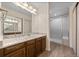 Well-lit bathroom featuring a vanity with granite countertop and a modern glass-enclosed shower at 7483 W Cedar Cir, Lakewood, CO 80226