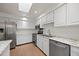 Bright kitchen featuring white cabinets, stainless steel appliances, granite countertops, and a skylight at 7483 W Cedar Cir, Lakewood, CO 80226
