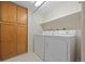 Bright laundry room features a washer, dryer, shelving, and built-in storage cabinets at 7483 W Cedar Cir, Lakewood, CO 80226