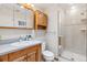 Bright bathroom with oak cabinets, a linen closet, and tiled shower at 138 S Holman Way, Golden, CO 80401
