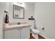 Bathroom with white vanity, tiled countertop, mirror, toilet, and hardwood floors at 15767 E 109Th Ave, Commerce City, CO 80022