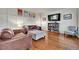 Cozy living room with hardwood floors, a leather sofa, and a built-in bookshelf, ideal for relaxation at 15767 E 109Th Ave, Commerce City, CO 80022