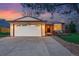 Charming home exterior featuring a garage, front door, and well-maintained yard at dusk at 12432 Bellaire St, Thornton, CO 80241