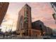 Modern high-rise condo building showcasing large windows, balconies, and a brick facade, set against a colorful sky at 1551 Larimer St # 1106, Denver, CO 80202