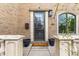 Close up of brick house's front door with a metal gate, potted plants, and a 'welcome' mat at 2330 N Emerson St, Denver, CO 80205