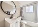 Bright bathroom with white subway tile, black and white flooring, modern fixtures, and a round mirror above the sink at 5222 Xanadu St, Denver, CO 80239