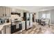 Well-lit kitchen featuring stainless steel appliances, gray cabinets, and an adjacent dining area with hardwood floors at 5222 Xanadu St, Denver, CO 80239