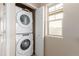 Convenient laundry room with stacked washer and dryer, plus a bright window for natural light at 12705 Ulster St, Thornton, CO 80602