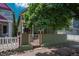 Charming green home with a well-kept front yard and white picket fence, shaded by a large tree at 616 W 1St Ave, Denver, CO 80223