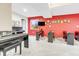 Large, bright basement features a red accent wall, carpet and multiple pianos for a recreational or musical space at 730 Pope Dr, Erie, CO 80516