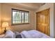 Cozy bedroom with wood closet and a window framing a beautiful view of the forest at 100 Apache Rd, Evergreen, CO 80439