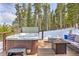 Outdoor deck with a hot tub, a cozy fire pit, and seating surrounded by serene woods for ultimate relaxation at 100 Apache Rd, Evergreen, CO 80439