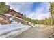 Charming cabin nestled on a hillside, surrounded by snow-covered rocks and lush pine trees at 100 Apache Rd, Evergreen, CO 80439