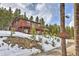 Two-story home with a wooden exterior, snow-covered surroundings, and natural landscaping at 100 Apache Rd, Evergreen, CO 80439