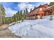 Cozy cabin featuring a spacious deck, nestled on a snow-covered hillside amongst towering trees at 100 Apache Rd, Evergreen, CO 80439