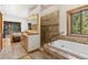 Bathroom with bathtub, tiled shower, double sinks, and forest views from the window at 72 Overlook Ct, Idaho Springs, CO 80452