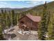Aerial view of a rustic log cabin home nestled in a lush forest with a driveway in the mountains at 72 Overlook Ct, Idaho Springs, CO 80452