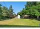 A spacious, grassy backyard with mature trees and partial fence, ideal for outdoor play and relaxation at 8140 Pennsylvania Way, Denver, CO 80229