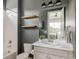 Modern bathroom features white vanity, wood shelves, and tub-shower combination with crisp white tile at 27653 E Euclid Dr, Aurora, CO 80016