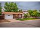 Charming two-story brick home with a well-maintained lawn, mature trees, a driveway, and an attached garage at 1583 Skeel St, Brighton, CO 80601