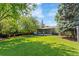 The backyard features a well-maintained lawn, a wooden fence, a deck, and mature trees at 5525 E Bails Dr, Denver, CO 80222