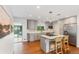 Bright kitchen with stainless steel appliances, gray cabinets, stylish pendant lights, island with cooktop and seating, hardwood floors at 5525 E Bails Dr, Denver, CO 80222