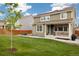 Green backyard with lawn, porch, fence, and view of a two-story home with solar panels at 16341 Clayton St, Thornton, CO 80602