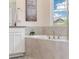 Bathroom features a soaking tub with stone surround, neutral walls, and a view to the outdoors at 16341 Clayton St, Thornton, CO 80602