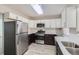 Modern kitchen with stainless steel appliances, white upper cabinets, and dark lower cabinets, showcasing style and functionality at 384 S Decatur St, Denver, CO 80219