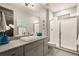 Modern bathroom featuring granite counters, gray cabinets, and tiled shower with glass doors at 16370 Graham Peak Way, Broomfield, CO 80023